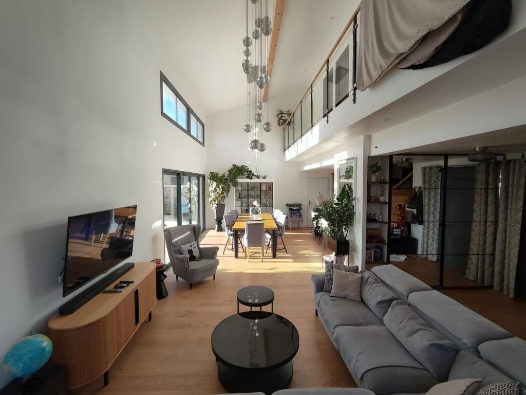 un grand salon avec un canapé et une télévision dans l'établissement La villa du bonheur, à Puilboreau