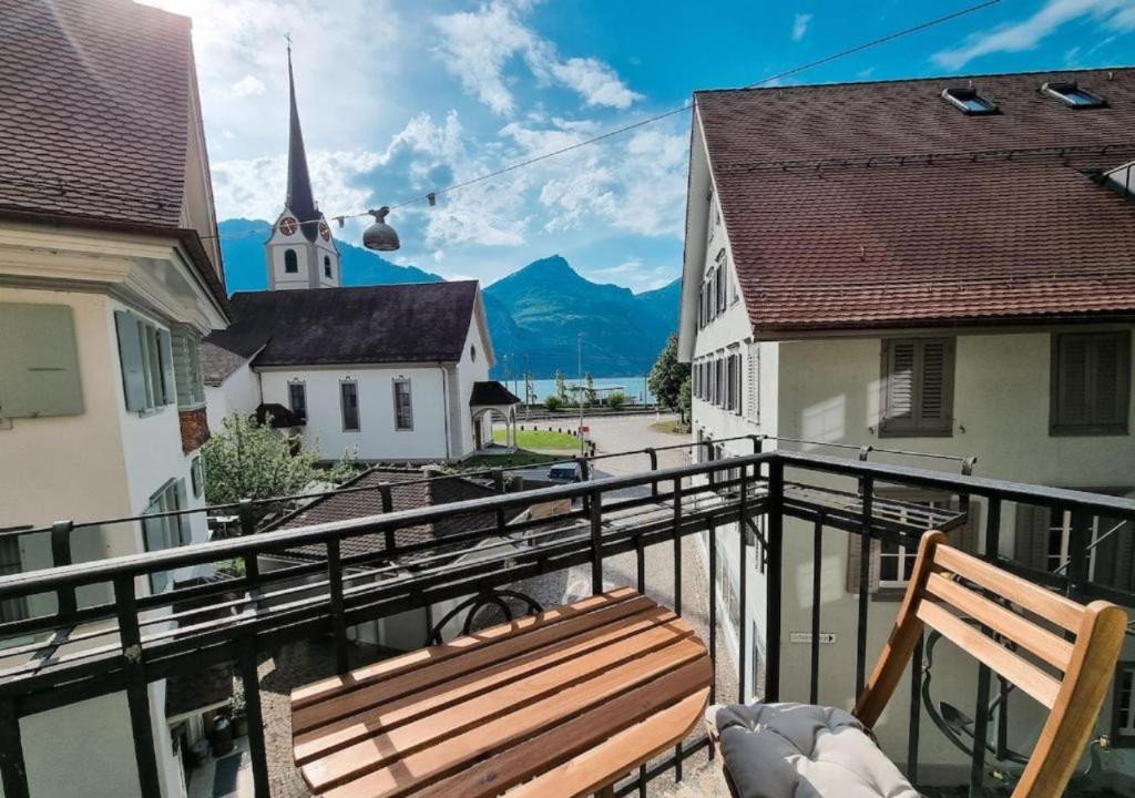 a wooden bench sitting on a balcony with a church at Paradise mit Seesicht in Fluelen