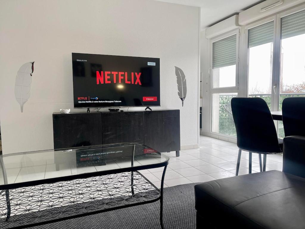 un salon avec une télévision, une table et des chaises dans l'établissement Aeroport d'Orly , Parking privé, à Orly