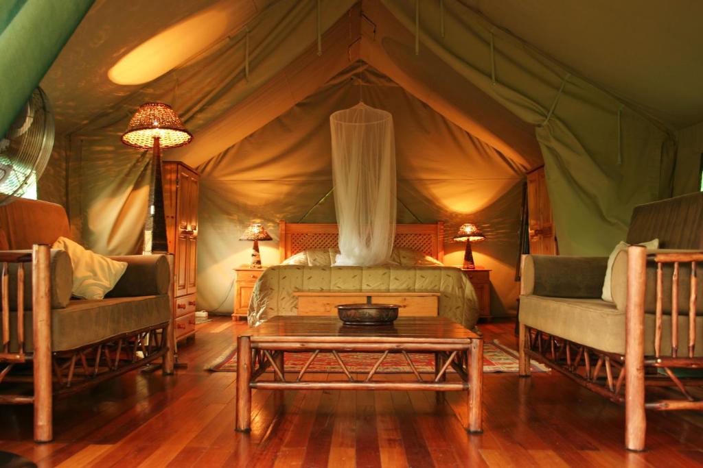 a bedroom in a tent with a bed and two chairs at Jackalberry Ridge by Dream Resorts in Marloth Park