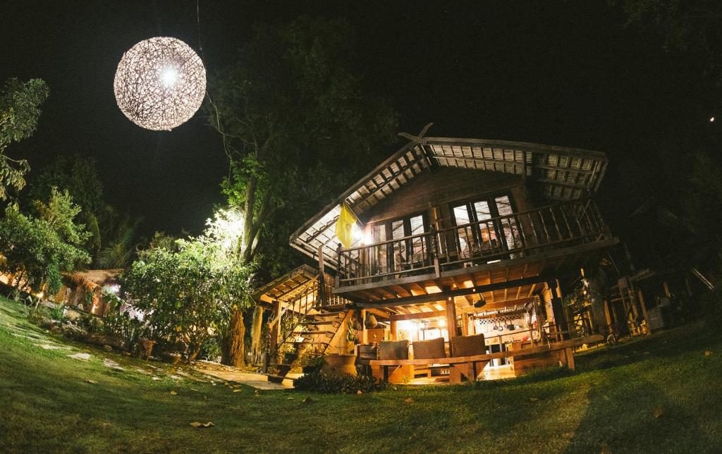 uma grande casa de madeira à noite com uma bola de discoteca em Rice Barn And Rooms em Hang Dong