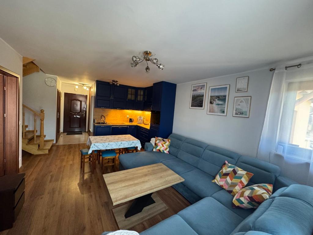 Una sala de estar con un sofá azul y una mesa. en Apartament Błękitny, en Krynica Morska