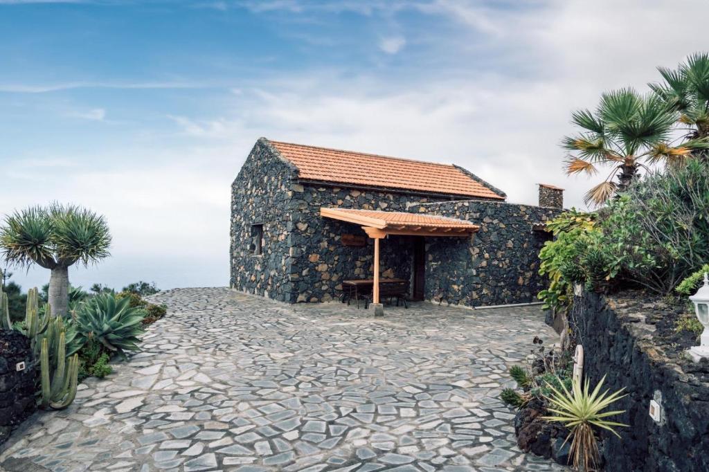 a stone house with a roof on a stone path at Casa Las Sabinas in Guarazoca