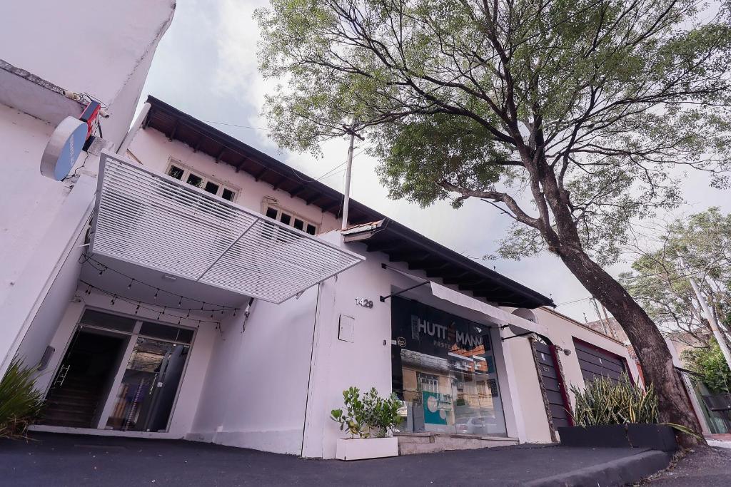 Un edificio blanco con un árbol delante. en Habitación céntrica con desayuno y baño privado, en Asunción
