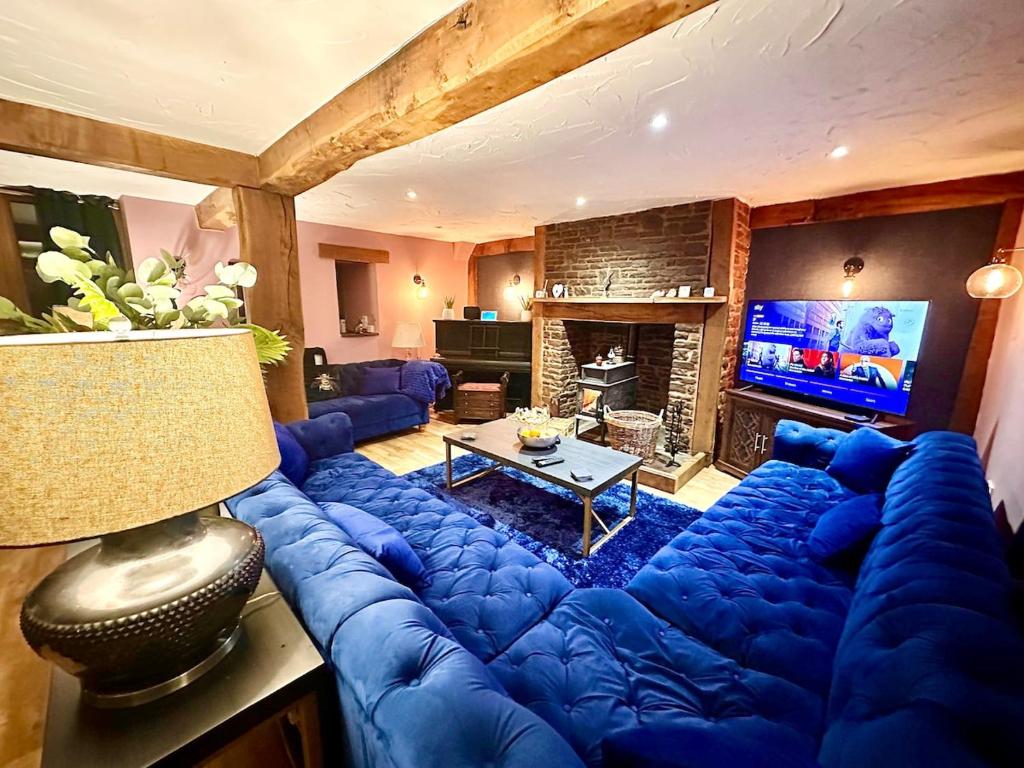 - un grand canapé bleu dans le salon avec une télévision dans l'établissement Luxury 4 bed former hay loft SLEEPS 6, à Usk