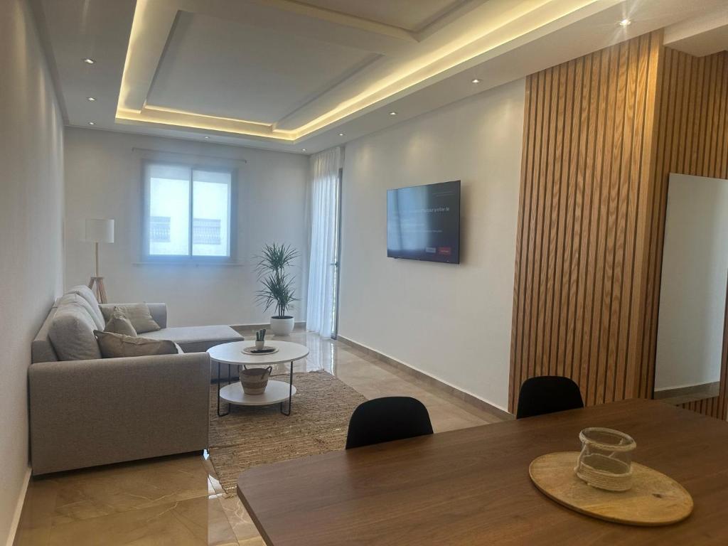 a living room with a table and a couch at Joli appartement proche de la plage in Agadir
