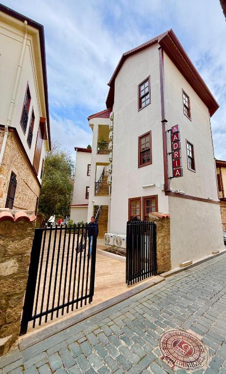 a white building with a black gate on a street at Adria Inn in Antalya