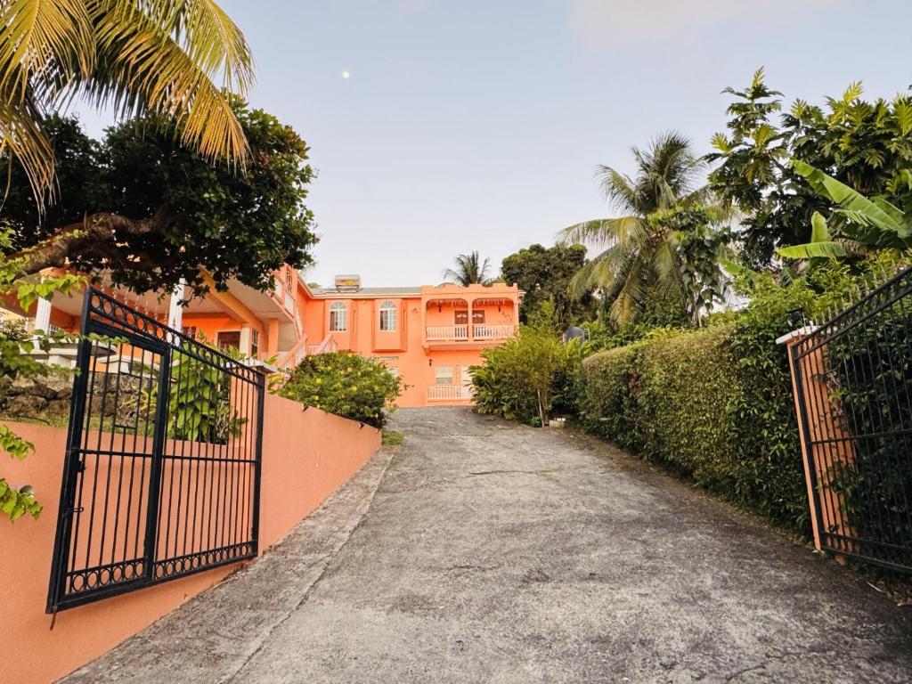 a driveway leading to a orange house with a gate at Anne Marie Villas in Castries