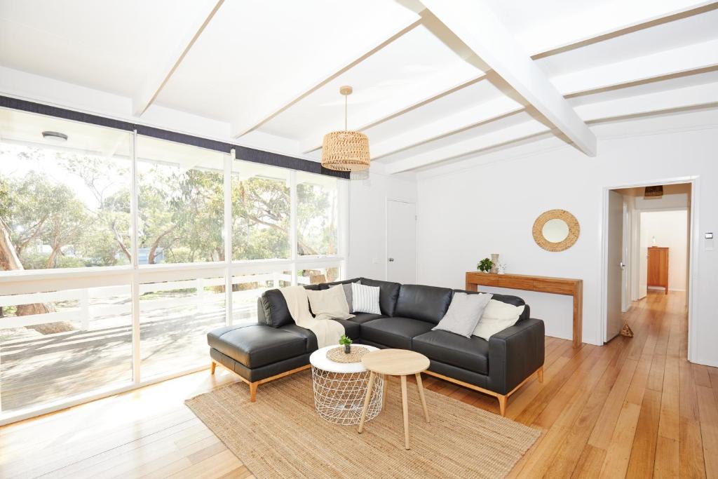 a living room with a black couch and a table at The little Beach Retreat in Anglesea