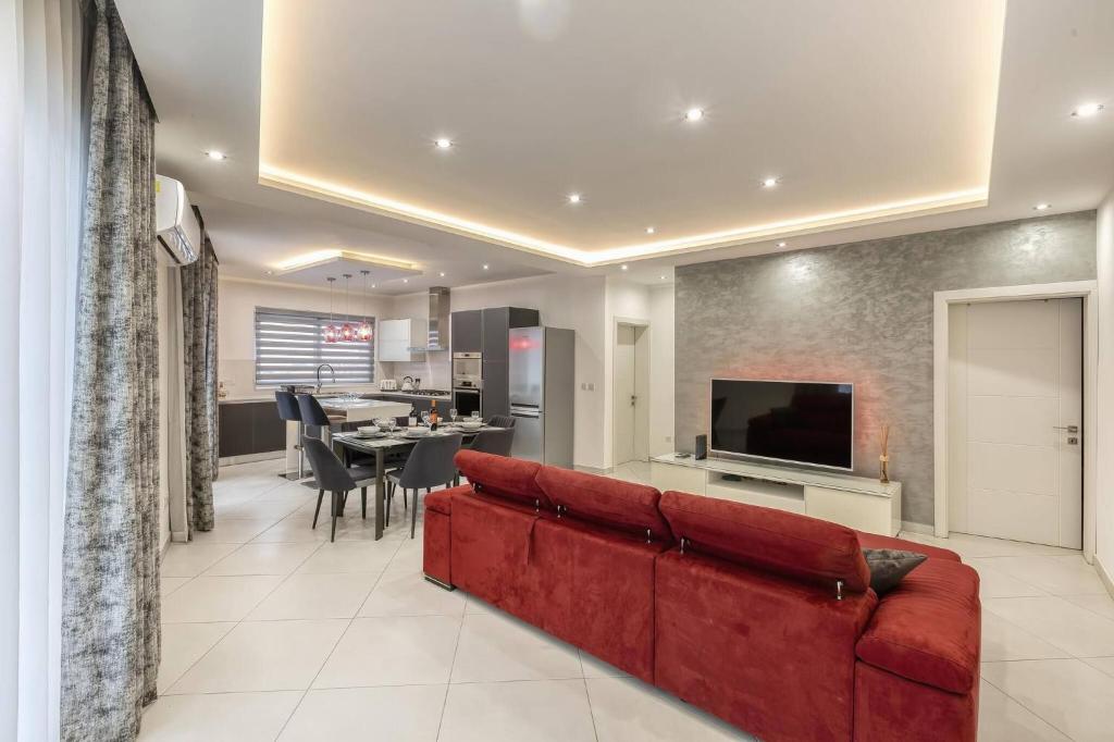 a living room with a red couch and a television at Luxury Cosy 3 Bedroom Apt in Gzira, close to Sliema StJulians by walk in Il-Gżira