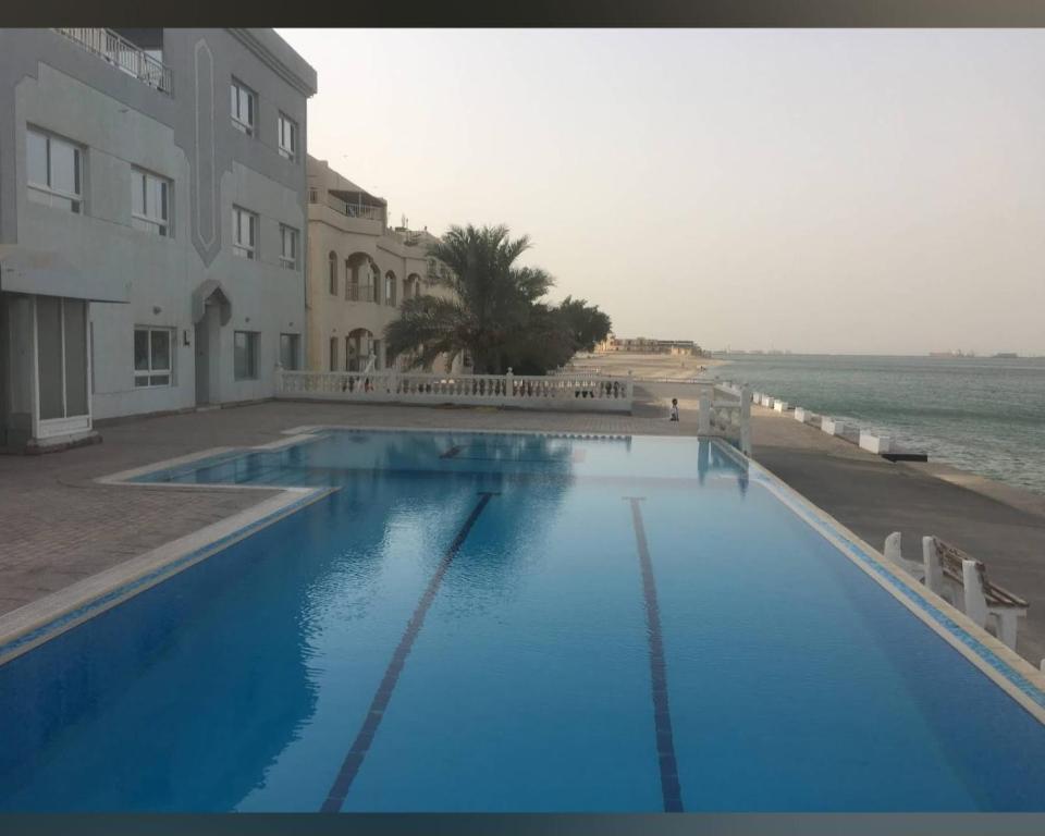 a large blue swimming pool next to a beach at Mangaf Kuwait Family Venus Flat- Beach access in Kuwait