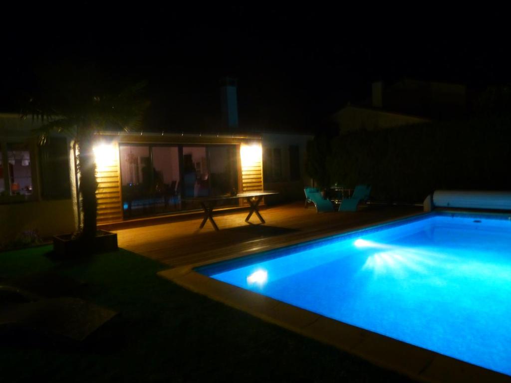 - une piscine avec une table et des lumières la nuit dans l'établissement ré tour de plage, à Saint-Martin-de-Ré