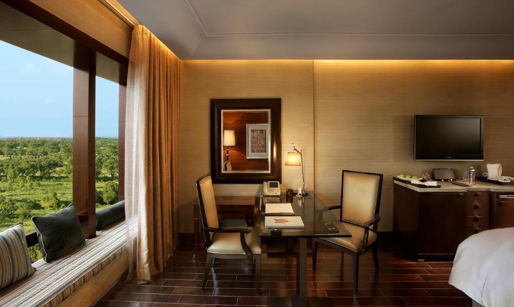 a hotel room with a desk and a bed and a window at The Leela Ambience Gurugram Hotel & Residences - The Luxury Urban Sanctuary in Gurgaon