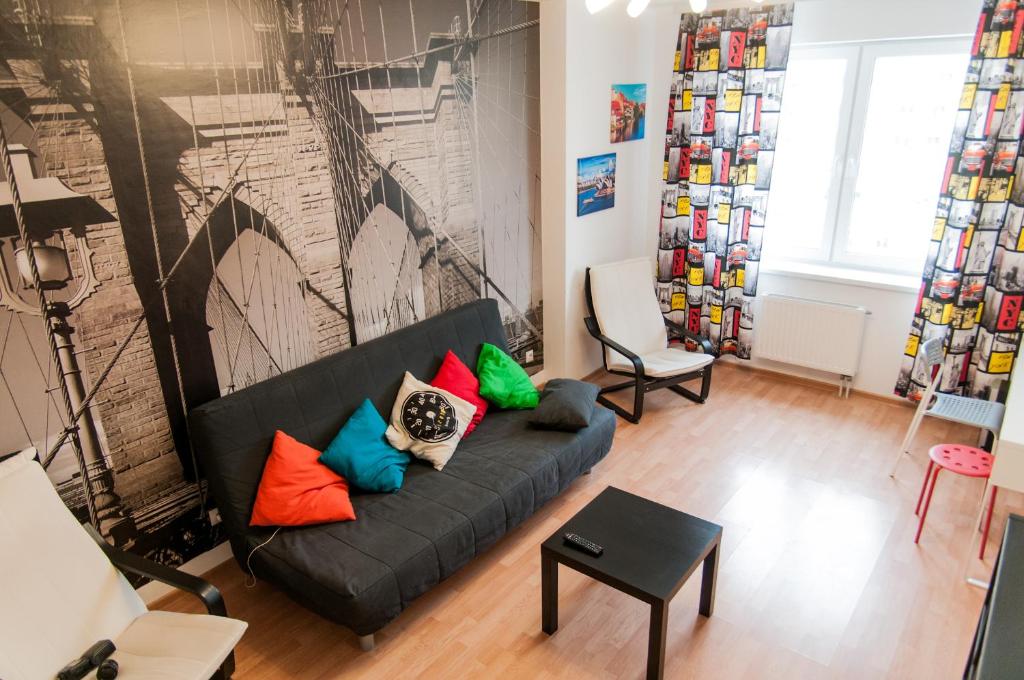a living room with a black couch with colorful pillows at Nice Days Hostel in Yekaterinburg