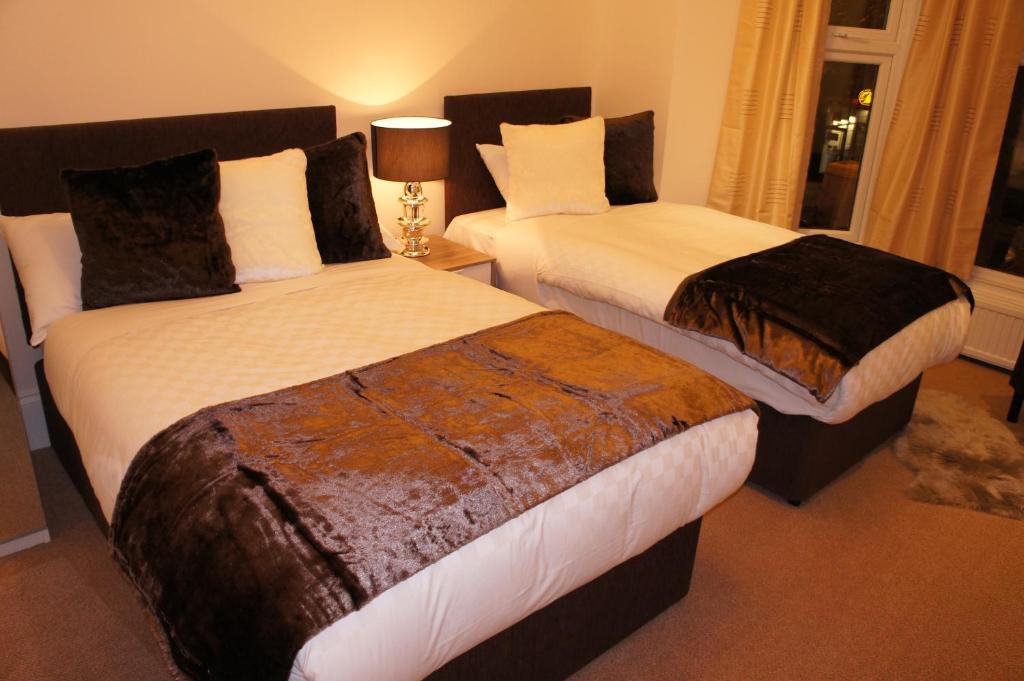 two beds in a hotel room withskirts at Sapphire Hotel London in London