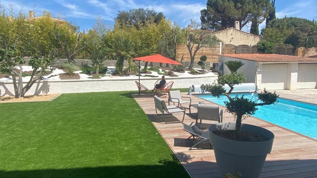 un homme assis dans une chaise à côté d'une piscine dans l'établissement Villa Ali avec piscine et Jacuzzi a450m du la mer!, à La Ciotat