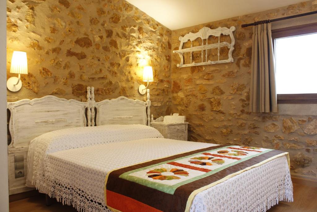 1 dormitorio con 2 camas y pared de piedra en Mas Dauden, en Campredó