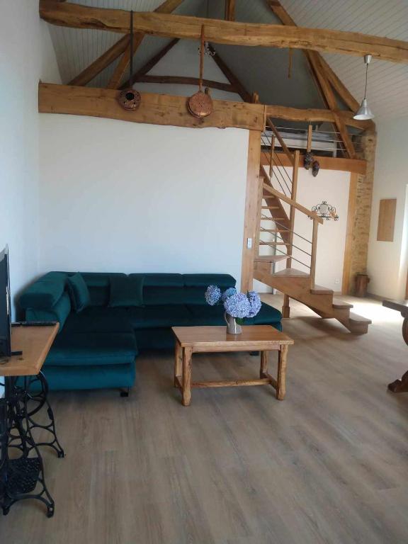 - un salon avec un canapé vert et une table en bois dans l'établissement La Grange du Poussié, à La Salvetat-Peyralès