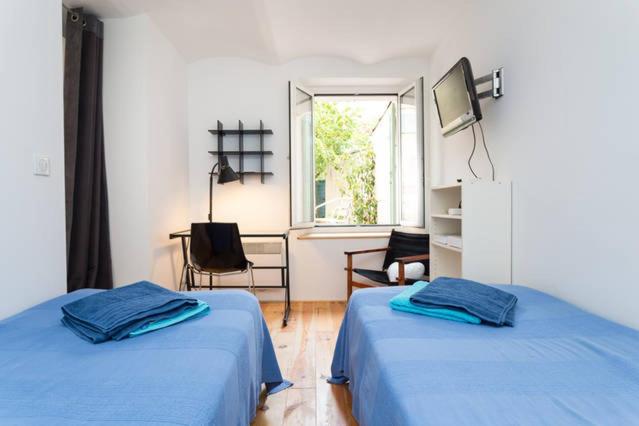 une chambre avec deux lits, un bureau et une fenêtre dans l'établissement Appartement avec jardin, à Cannes
