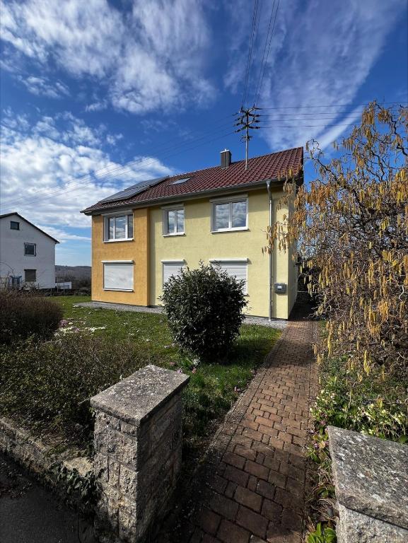 a yellow house with a brick path in front of it at Ferienwohnung im Heiligenberg in Langenburg