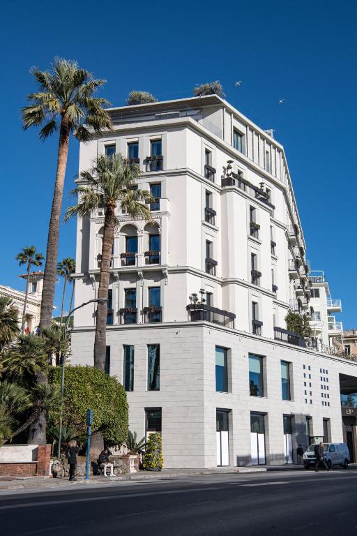 Un edificio blanco con palmeras delante. en Europa Palace, en San Remo
