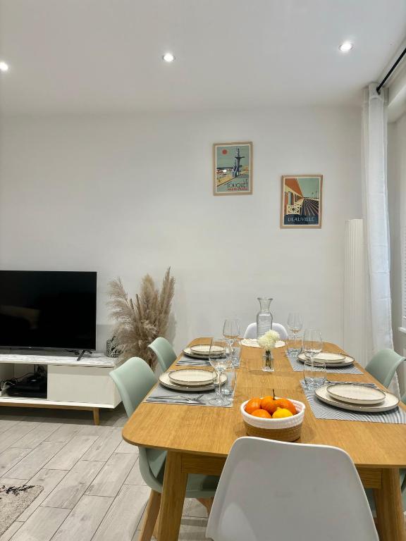 une salle à manger avec une table avec des chaises et une télévision dans l'établissement Le cocon du Touquet, à Le Touquet-Paris-Plage
