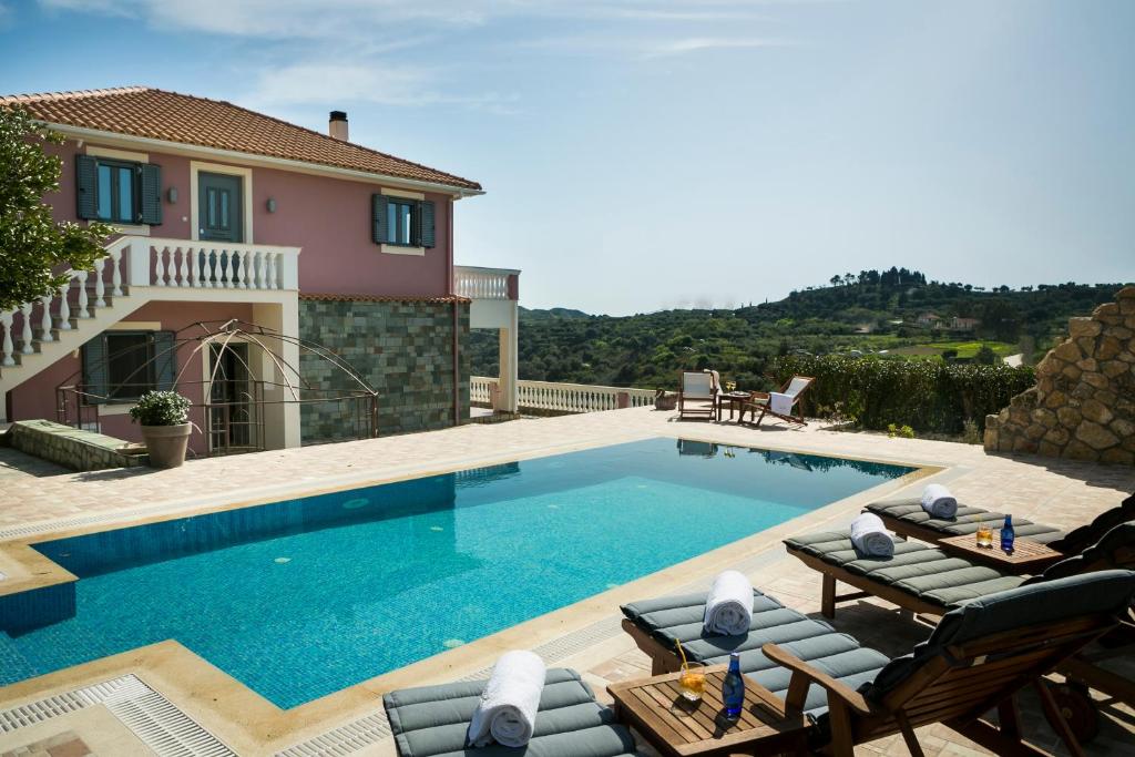 a swimming pool with chairs and a house at Villa Athinais in Lixouri