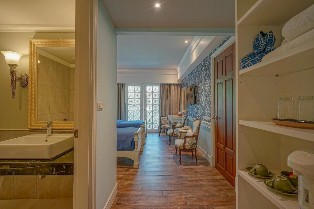 A suite-like bedroom and sitting area viewed from beside a marble bathroom vanity.