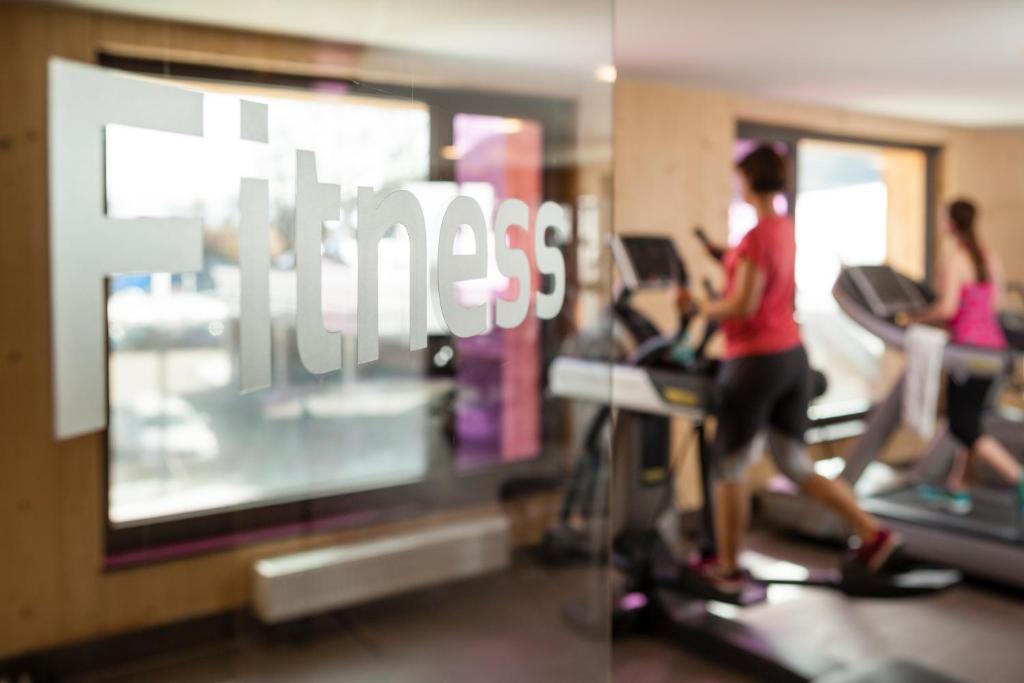 a woman running on a treadmill in a gym at Explorer Hotel Montafon in Gaschurn
