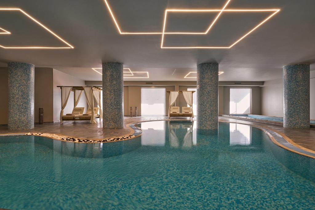 a swimming pool in a hotel with chairs and lights at Lindos Imperial Resort & Spa in Kiotari