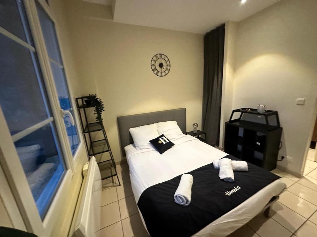 une chambre avec un lit et une horloge au mur dans l'établissement CHARMANT Studio 100 M Gare, à Tours