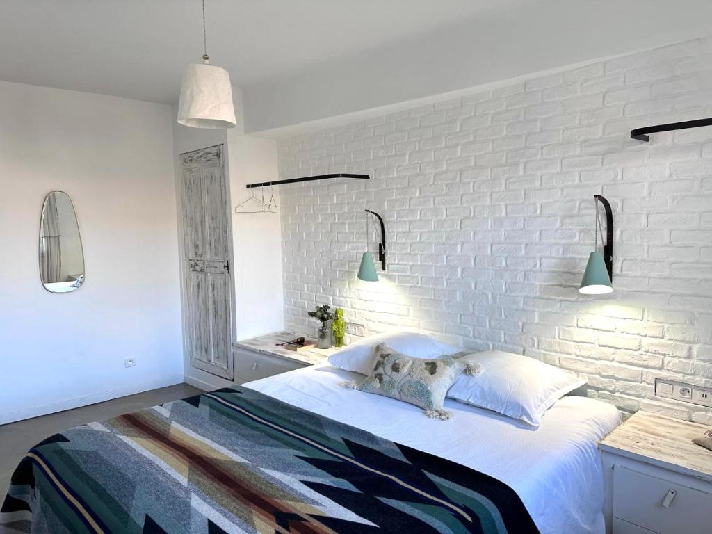 a bedroom with a white brick wall and a bed at Le 40 in LʼIsle-sur-la-Sorgue