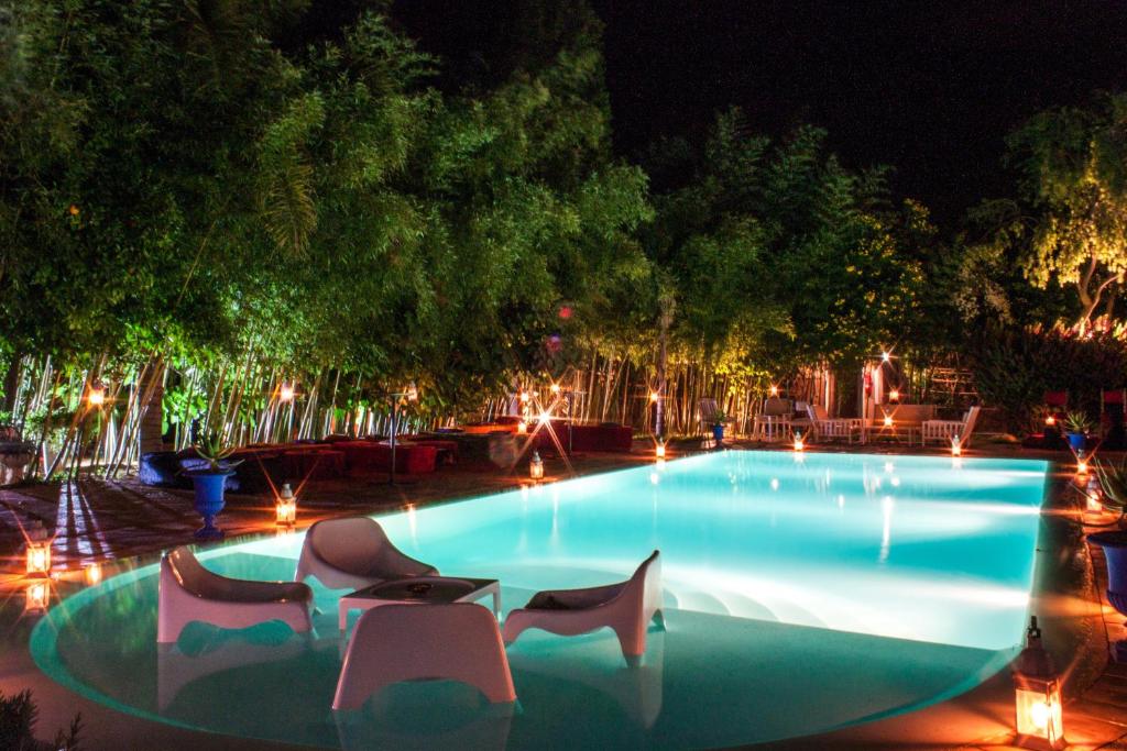 a swimming pool at night with chairs and lights at Le Bled Ferme in Marrakesh