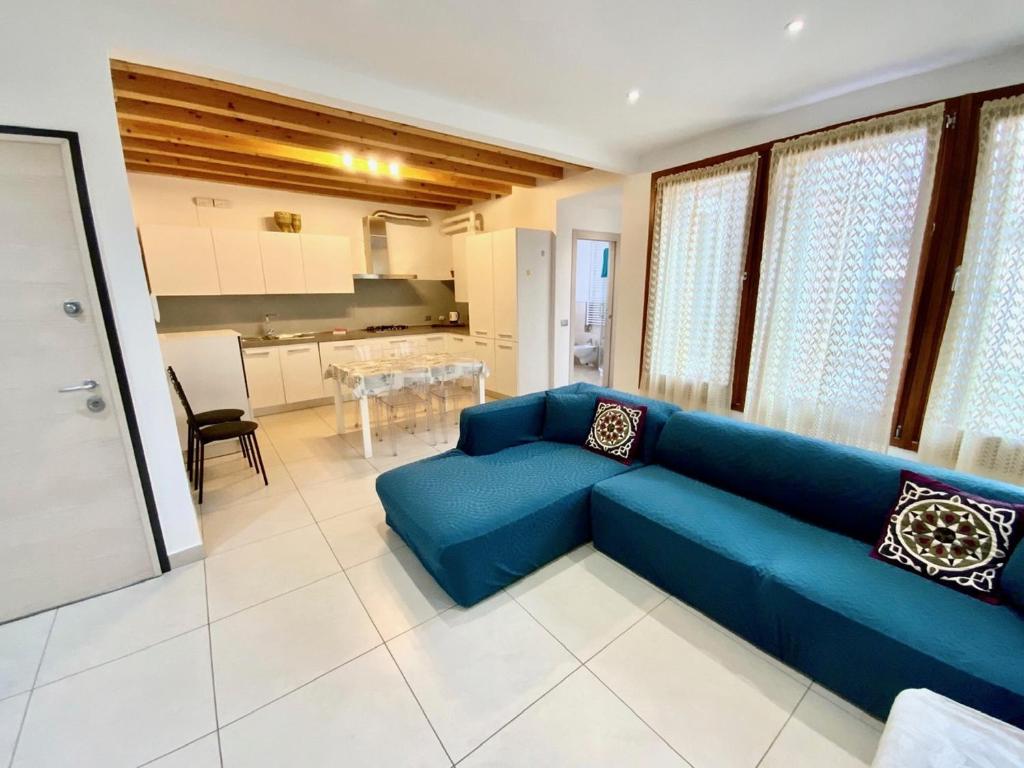 a living room with a blue couch and a kitchen at Palazzo Penzo Bellemo in Chioggia