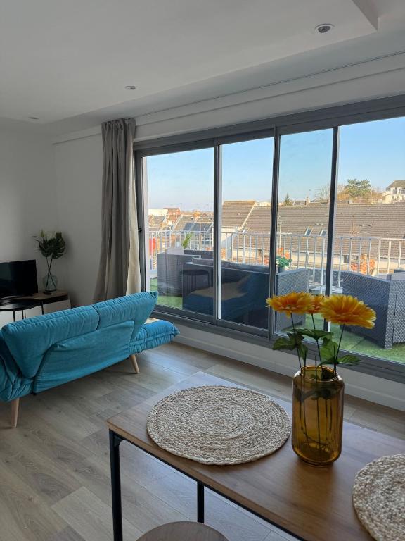 un salon avec un canapé bleu et une grande fenêtre dans l'établissement Studio cosy avec terrasse à deux pas de la gare, à Amiens