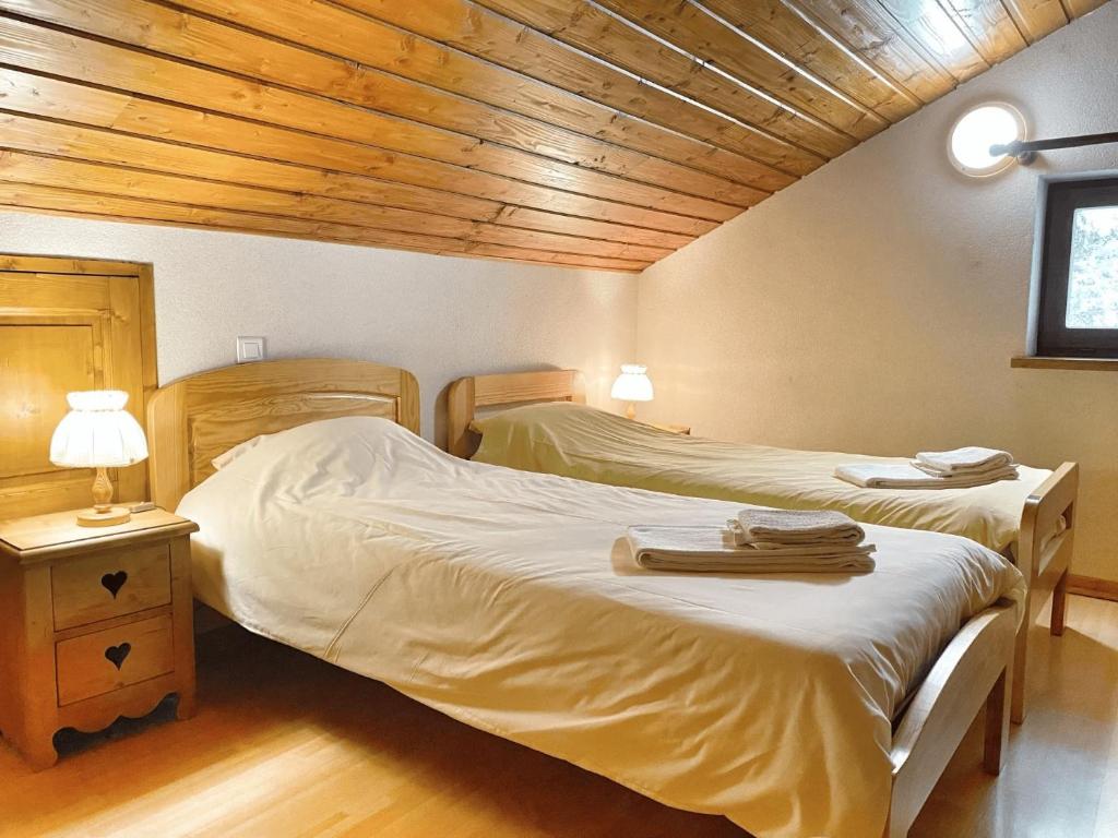 Habitación con 2 camas individuales y techo de madera. en Les Oulles 10, en La Chapelle-en-Valgodemard