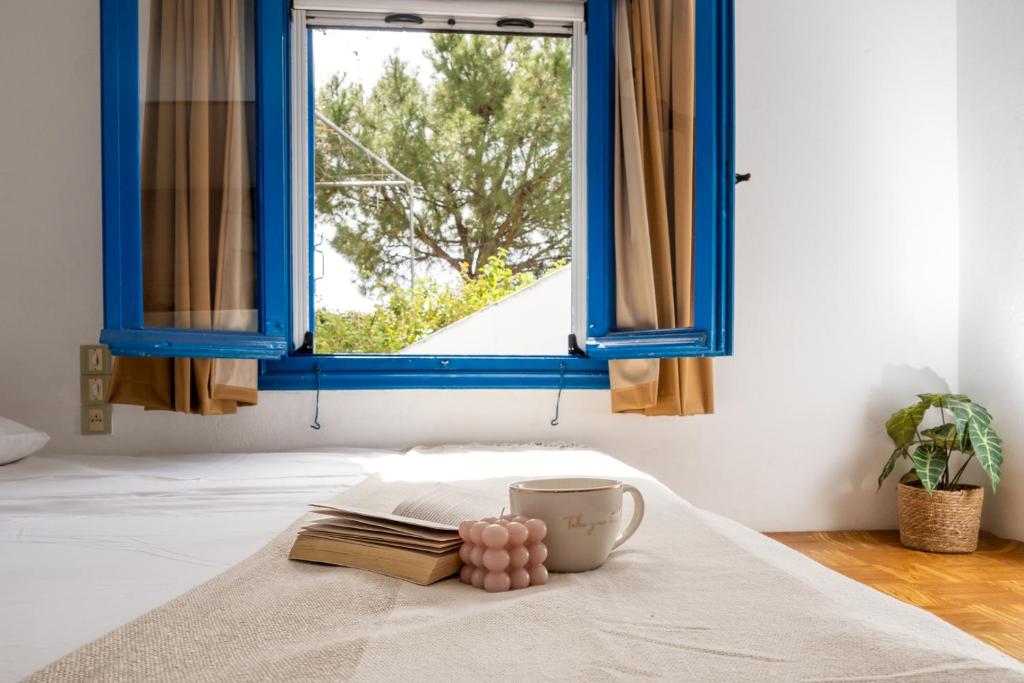 una mesa con un libro y una taza en una cama con ventana en Villa Panorama in Pefkos, en Pefki
