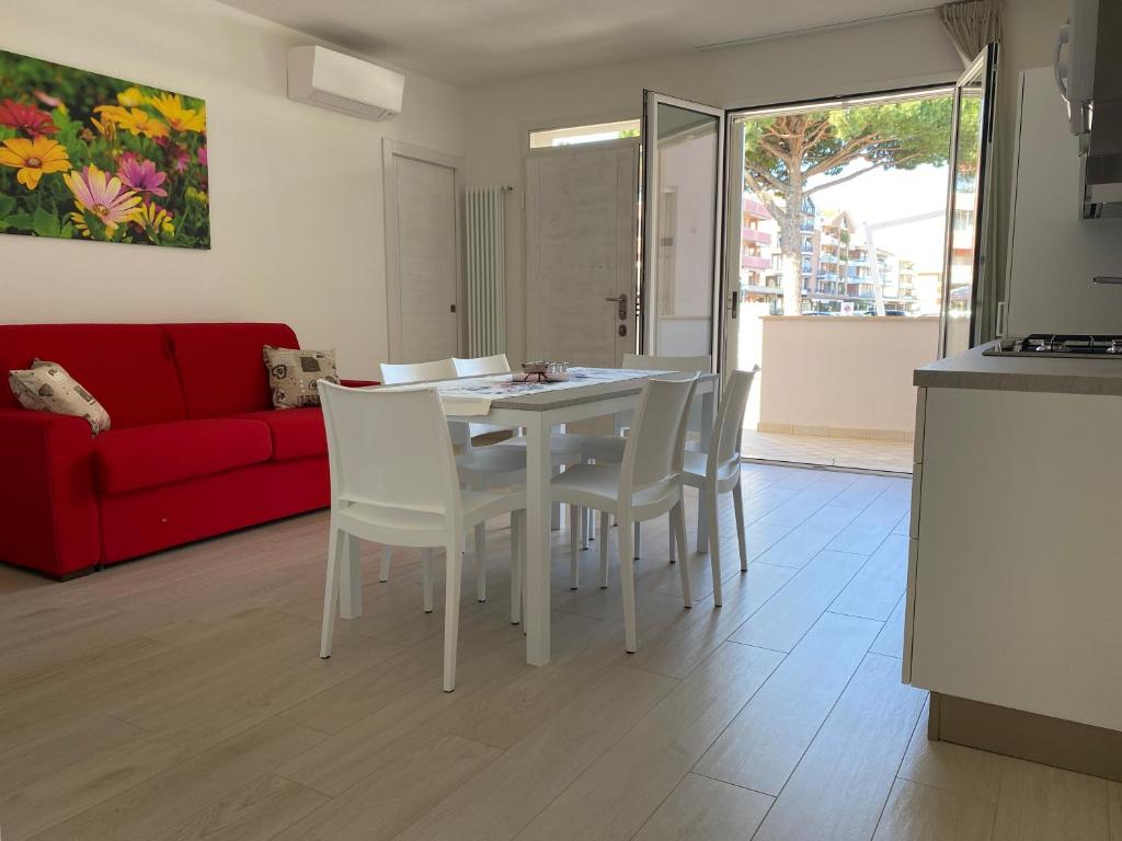 a living room with a table and chairs and a red couch at Le Casine di Cervia in Cervia