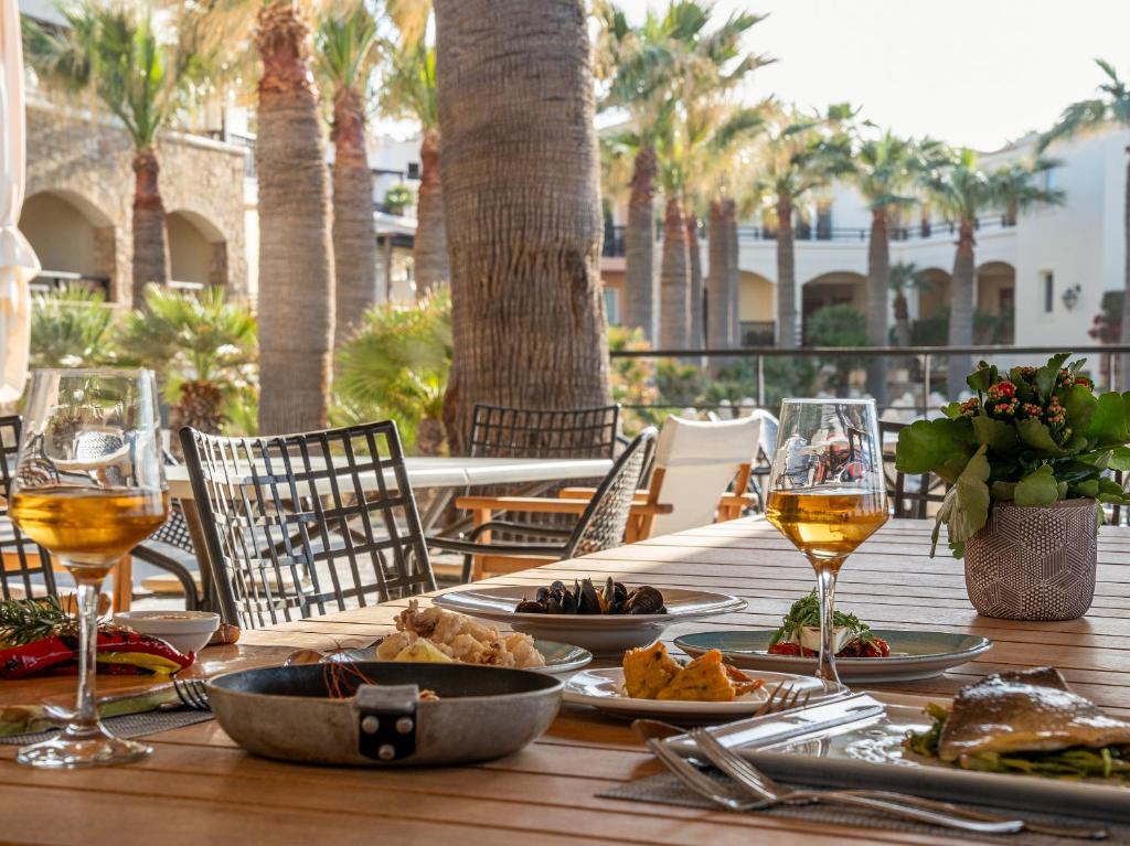 a wooden table with plates of food and glasses of wine at Grecotel Marine Palace & Aqua Park in Panormos Rethymno
