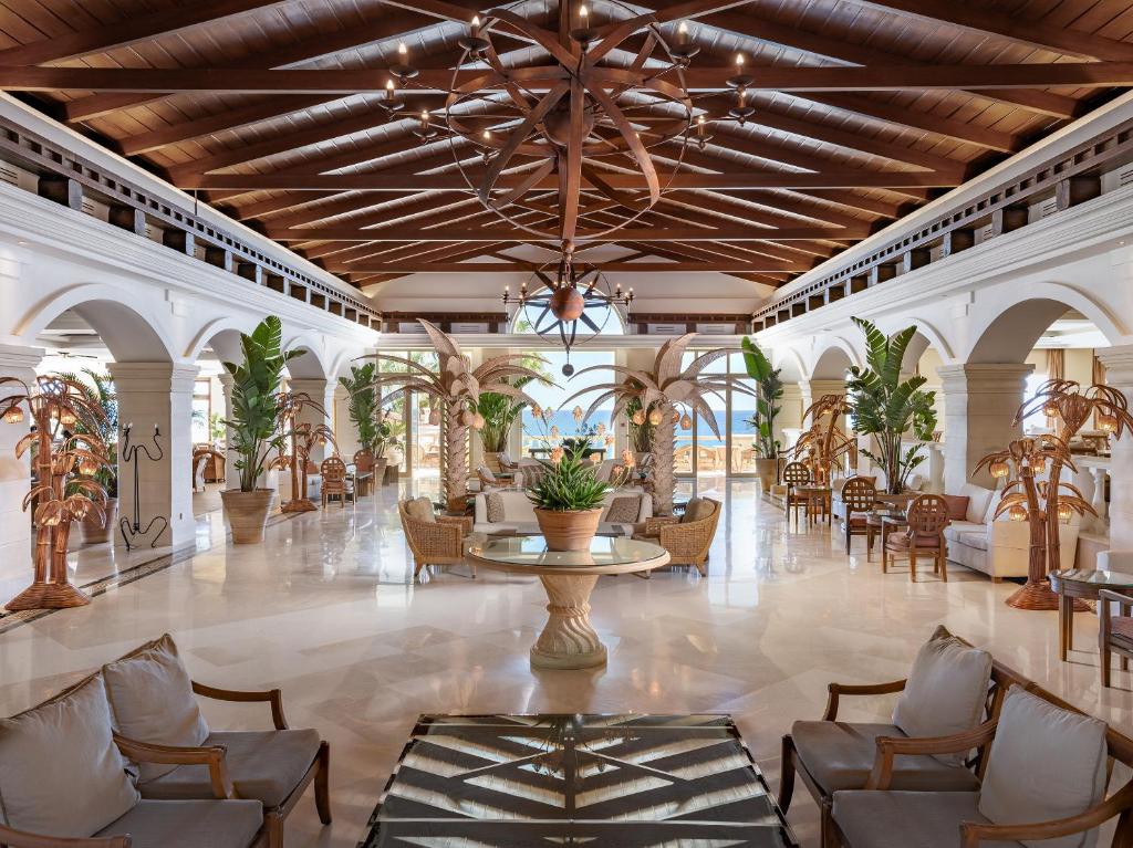 a lobby with a table and chairs and a chandelier at Grecotel Marine Palace & Aqua Park in Panormos Rethymno