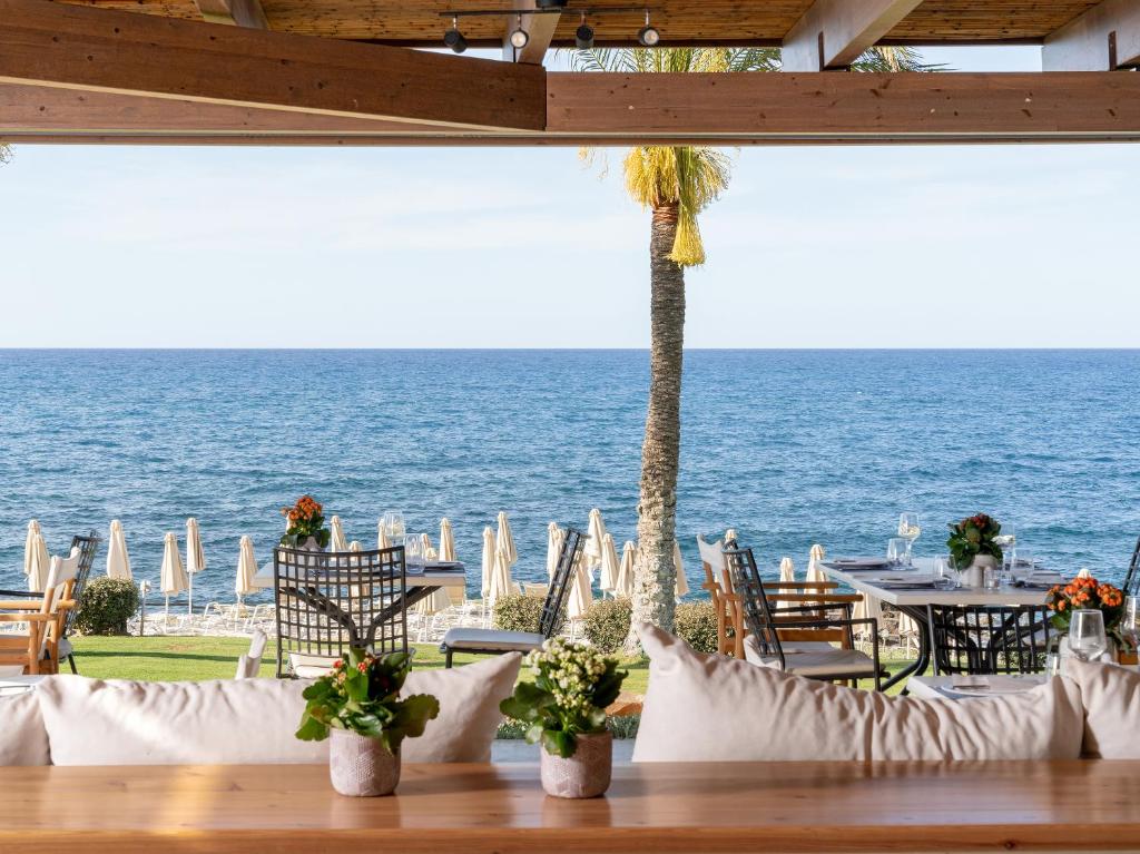 a table with chairs and a view of the ocean at Grecotel Marine Palace & Aqua Park in Panormos Rethymno