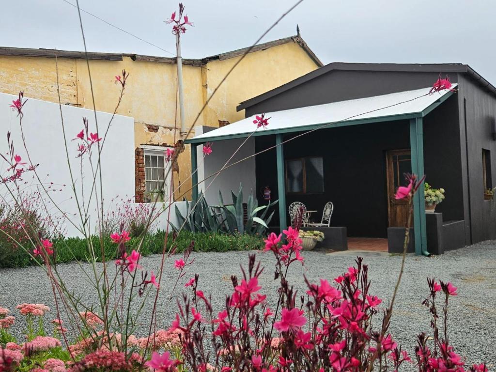 a house with a white awning and pink flowers at Rusgenot - Richmond, Karoo in Richmond
