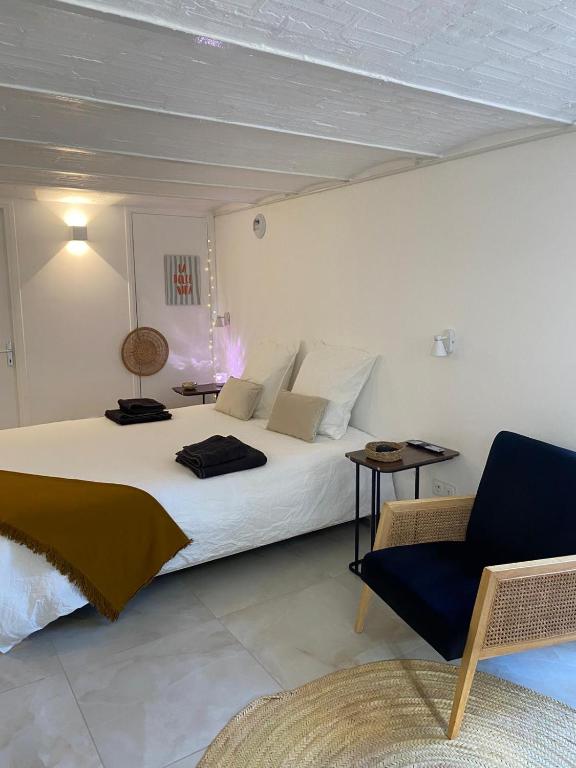 une chambre avec un grand lit blanc et une chaise dans l'établissement Le Cocon - proche gare avec jardinet - 2 adultes et 1 bébé, à Bois-le-Roi