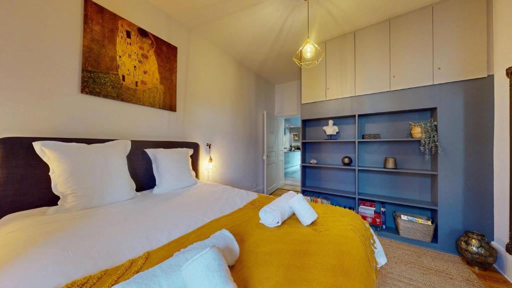 - une chambre avec un grand lit blanc et une couverture jaune dans l'établissement Le Leblois - Grande cuisine, à Strasbourg