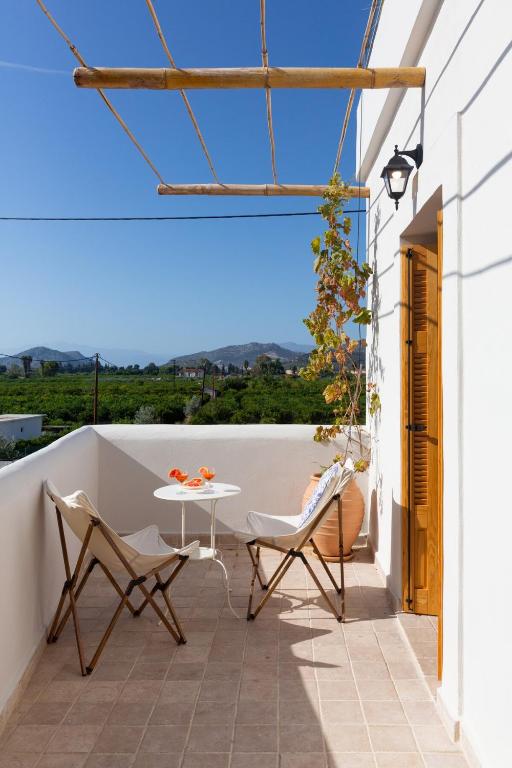 a balcony with a table and chairs on a white wall at Villa Plaka 16 "The Bordeaux"-Drepano Nafplio in Drepana