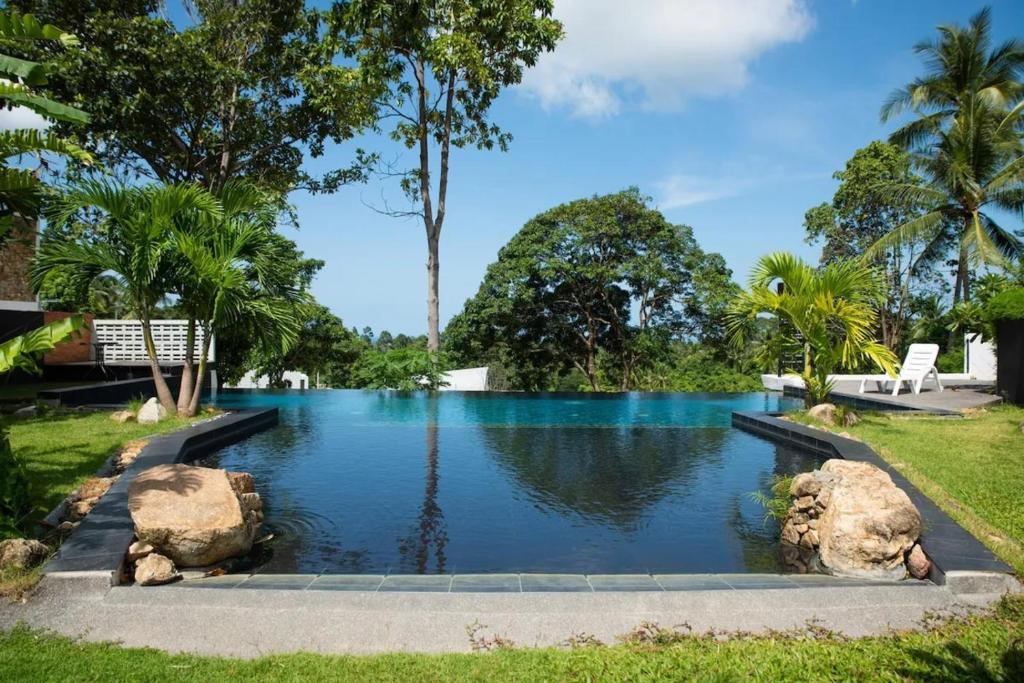 una piscina in un giardino con rocce in acqua di Holy View 2br Shared Pool & Seaview - Chaweng a Chaweng Beach