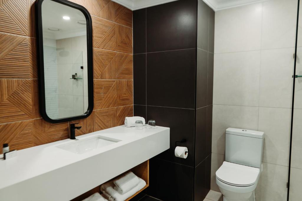a bathroom with a sink and a mirror and a toilet at Emerald Resort & Casino in Vanderbijlpark