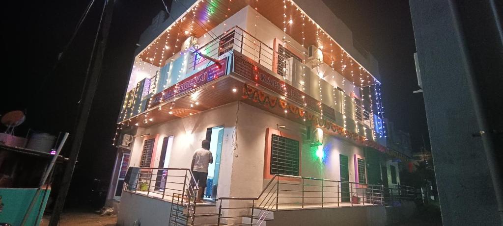 a man standing on the balcony of a building with lights at Kapila Residency Ellora in Ellora