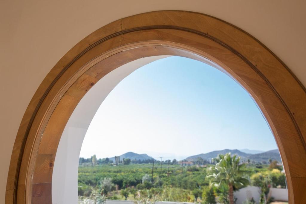 an arched window with a view of a field at Villa Plaka 16 - 'The Boat' - Drepano, Nafplio in Dhrepanon