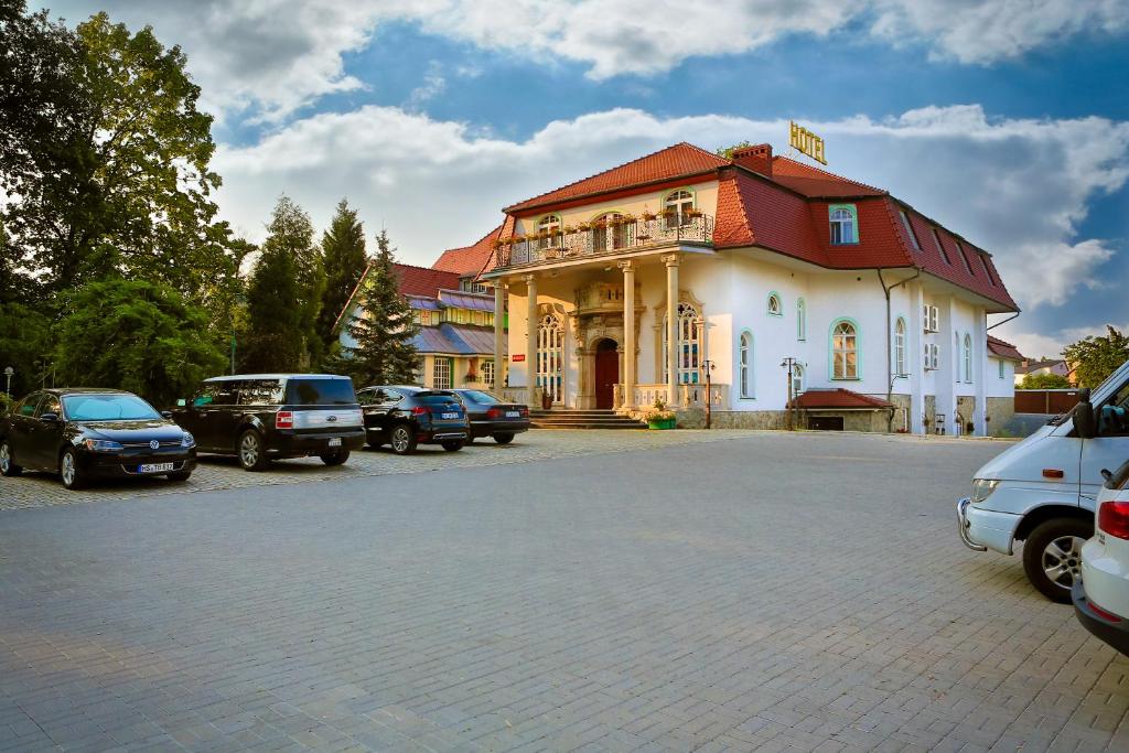 un gran edificio con coches estacionados en un estacionamiento en Hotel Garden en Bolesławiec